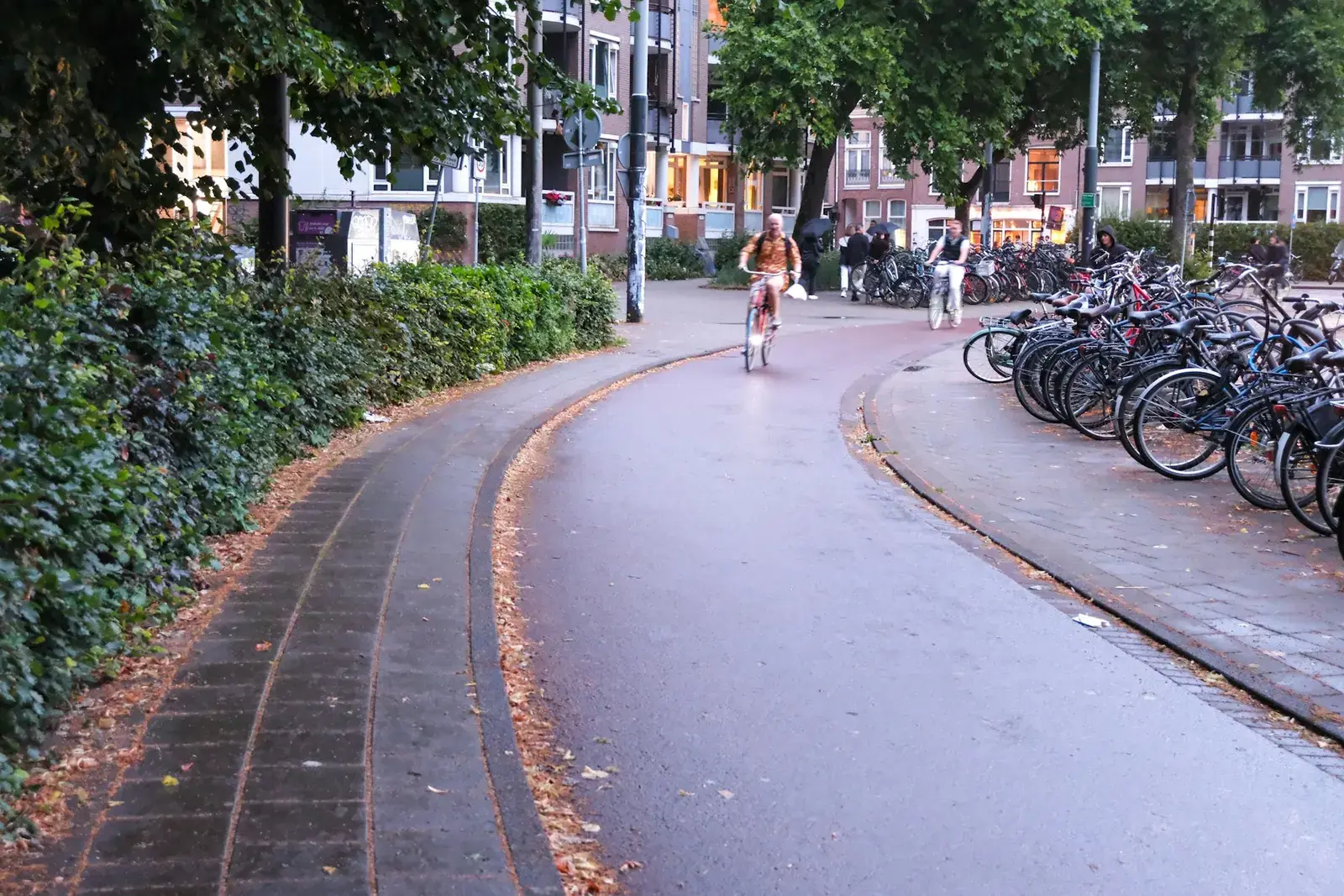 Fietsers op een nat fietspad in Amsterdam bij het vallen van de avond