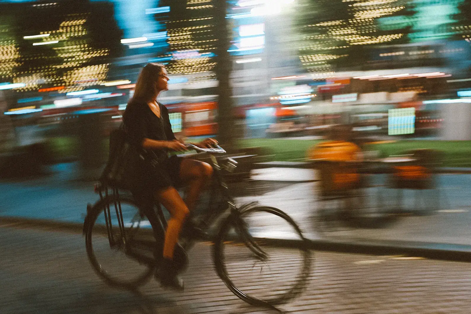 Een fietser in het avondlicht, met de stad in beweging op de achtergrond