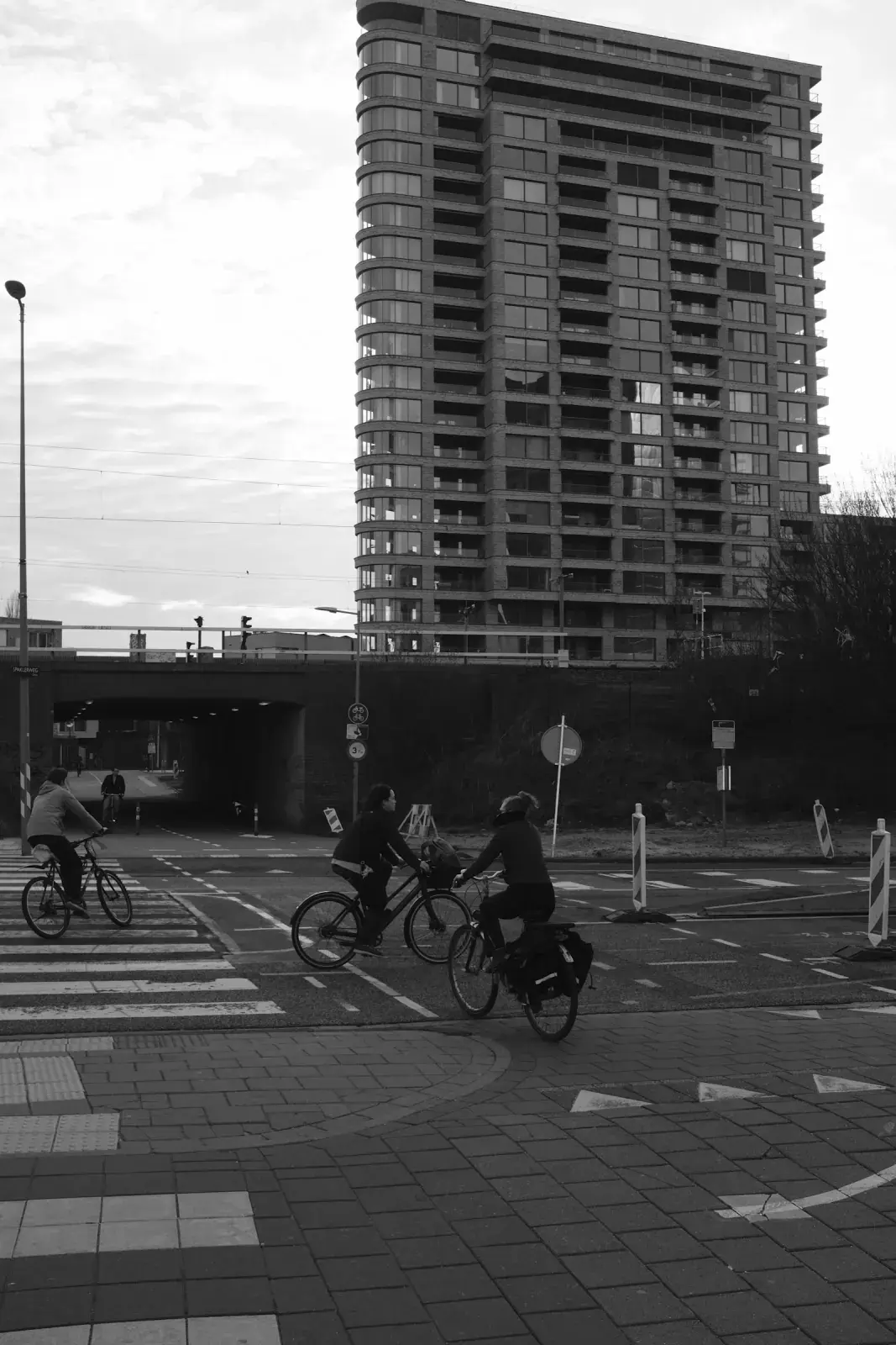 Fietsers steken over tussen moderne gebouwen, in zwart-wit