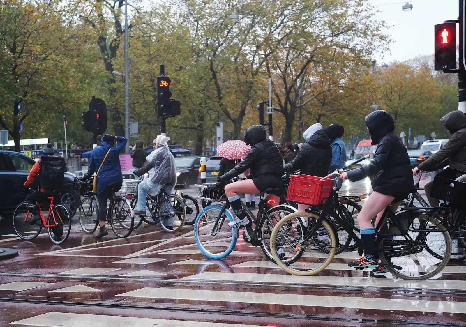 Fietsers wachten in de regen op een Amsterdamse kruising